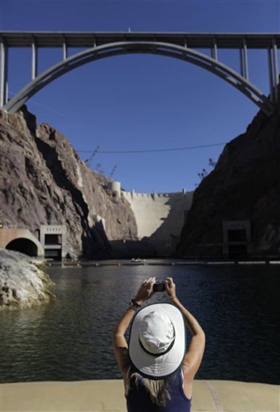 Dawna Robertson of San Diego, Calif., takes a photo of Hoover Dam and the newly completed bypass bridge Tuesday from a Black Canyon River Adventures commercial raft near Boulder City, Nev.